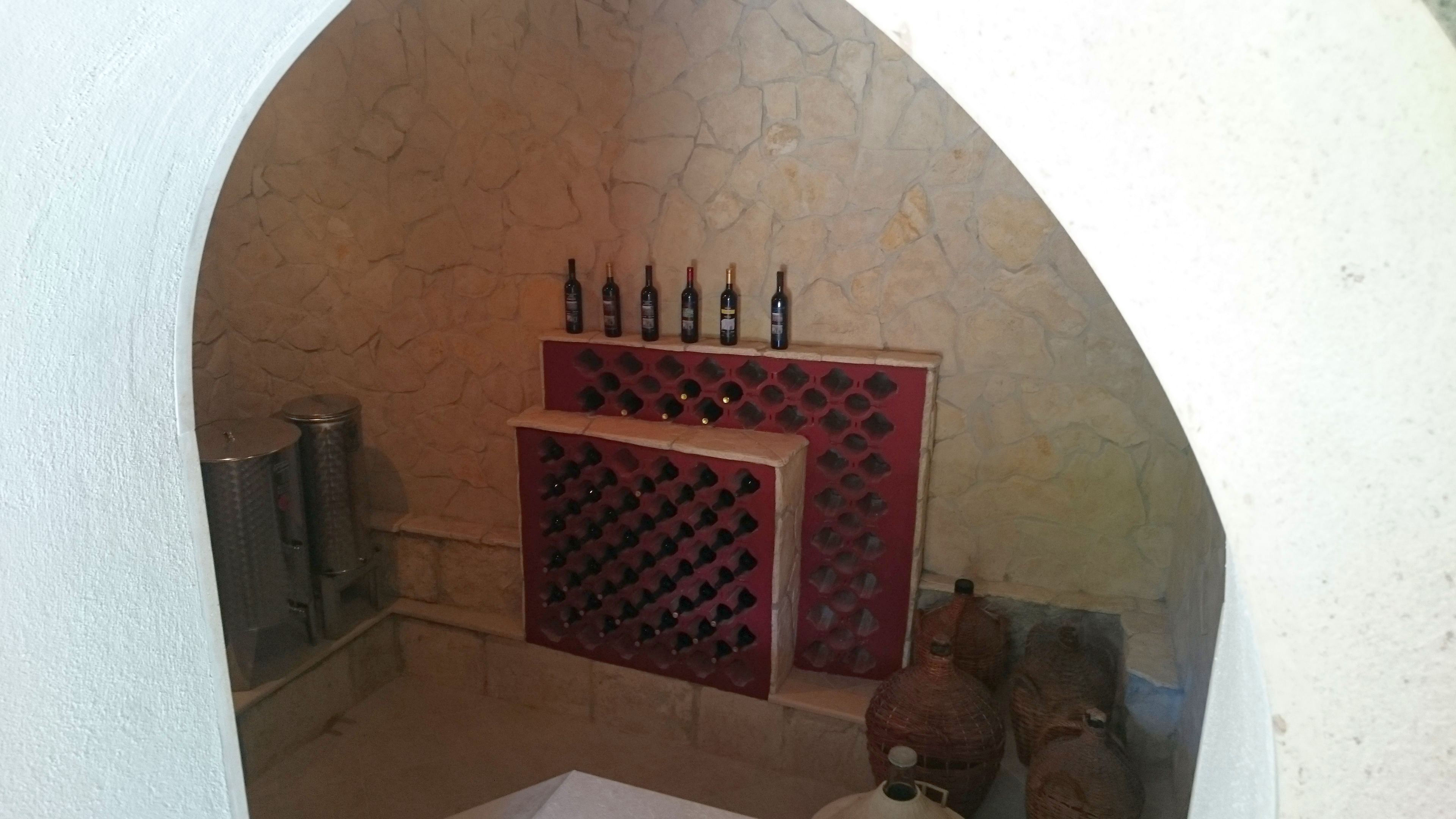 A wine cellar with a stone wall, wine racks, and a metal container.