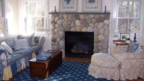 Una sala acogedora con chimenea de piedra, un sofá, un sillón y una mesa de centro.