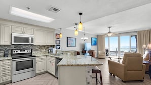 A modern kitchen with a central island, stainless steel appliances, and pendant lighting. - 104 Sterling Sands Oceanfront Paradise Found! Steps to the Beach! (Destin)