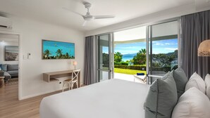 Habitación de hotel moderna con una cama grande, un escritorio y vistas al océano.