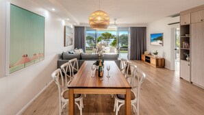 Un comedor moderno con una mesa de madera, sillas blancas y una lámpara colgante.