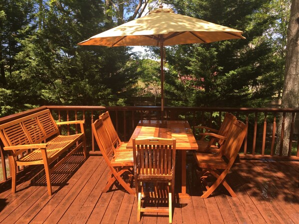 Una terraza de madera con una mesa y sillas, rodeada de árboles.