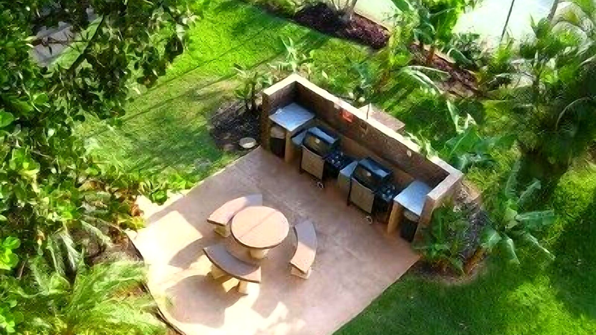 An outdoor patio with a round table and chairs, a built-in grill, and a small seating area.
