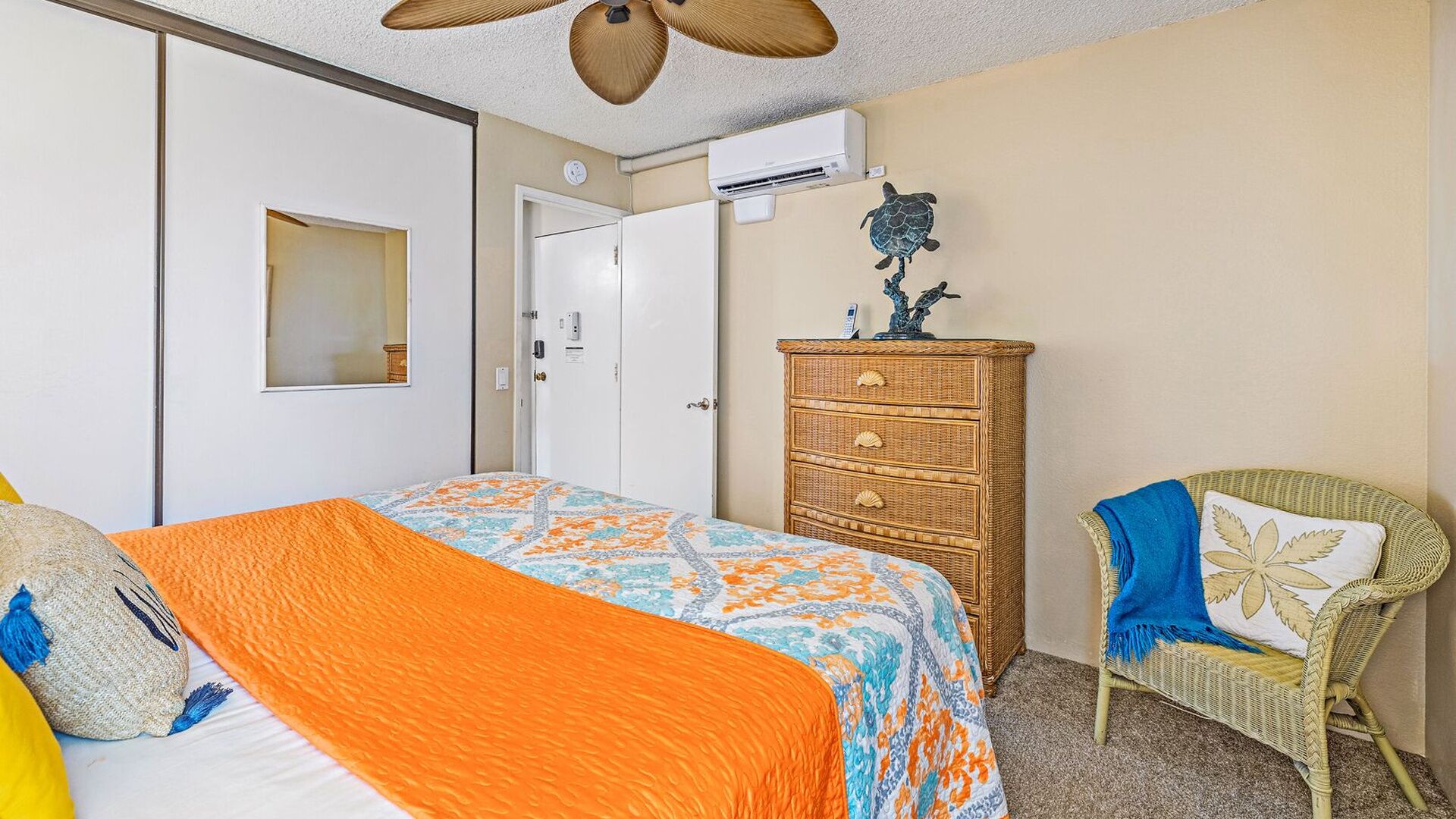 Une chambre à coucher avec un lit, une commode, une chaise et un ventilateur de plafond.