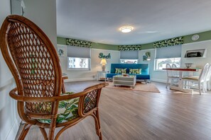 A living room with a blue sofa, a wooden chair, and a dining table with chairs. - OCEAN VIEW studio apt BEST LOCATION (New Smyrna Beach)