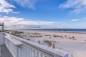 A beach view from a wooden deck with a railing, a sandy beach, and the ocean in the background. - OCEAN VIEW studio apt BEST LOCATION (New Smyrna Beach)