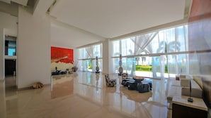 A spacious, modern hotel room with large windows, a polished floor, and contemporary furnishings.