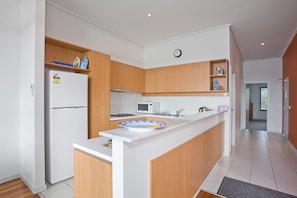 Una cocina moderna con armarios de madera, microondas integrado y pileta de acero inoxidable.
