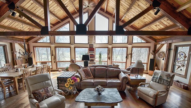 A spacious living room with a high wooden ceiling, large windows, a sofa, armchairs, a coffee table, and a dining area. - Spectacular Spirit Dancer 4 bedrooms, 1 den w/bed, Luxurious on 60 private acres (Etlan)