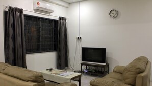 A living room with a TV, two leather sofas, a coffee table, and a window with curtains. - Homey 55 Cottage (Kuching)