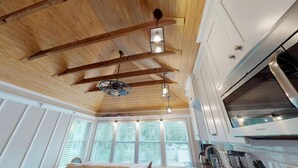 Una cocina con vigas de madera, armarios blancos y una campana extractora de acero inoxidable.