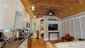 Una cocina moderna con armarios blancos, electrodomésticos de acero inoxidable y techo de madera.