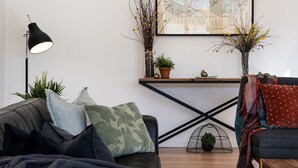 A modern living room with a sofa, a coffee table, a floor lamp, and decorative plants. - Lake Como Villa- Lake Daylesford on your doorstep (Daylesford)