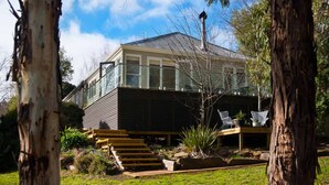 A modern house with a large glass balcony, a wooden deck, and a staircase leading to a covered outdoor area. - Lake Como Villa- Lake Daylesford on your doorstep (Daylesford)
