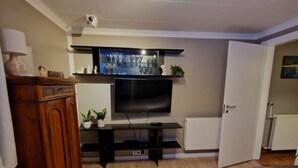 A living room with a television, wooden cabinet, and a door leading to another room. - Apartment close to center of town in a quiet area (Akureyri)