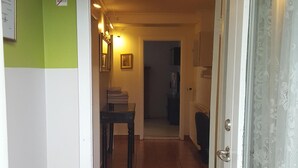 A hallway with a checkered floor, a table with chairs, and a door with a lace curtain. - Apartment close to center of town in a quiet area (Akureyri)
