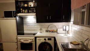 A compact kitchen with a microwave, oven, washing machine, and a sink. - Apartment close to center of town in a quiet area (Akureyri)