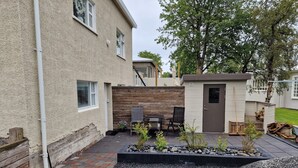 A patio area with a seating arrangement, a small garden bed, and a wooden fence. - Apartment close to center of town in a quiet area (Akureyri)