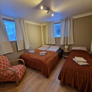 A room with two beds, a chair, and a ceiling fan.