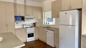A kitchen with beige cabinets, a white refrigerator, a stove, a microwave, and a dishwasher. - 35 YAMBA STREET Dog friendly (Yamba)