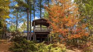 A cabin with a wooden deck and a staircase leading to a second level.