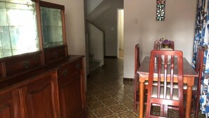 A dining area with a wooden table and chairs, a patterned floor, and a staircase leading to another room.