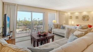 A spacious living room with a balcony, a television, and a sofa set.