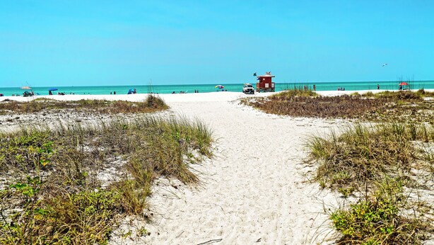 A sandy beach path leading to a lifeguard tower.