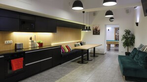 Una cocina moderna con zona de comedor, que incluye una encimera negra, armarios de madera y un sofá verde.
