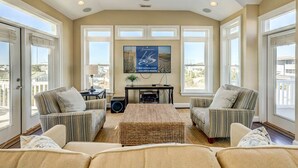 A spacious living room with a large TV, two sofas, a coffee table, and a fireplace. - Windjammer | 160 ft from the beach | Private Pool, Hot Tub (Virginia Beach)