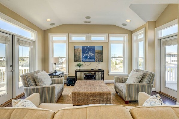 A spacious living room with a large TV, two sofas, a coffee table, and a fireplace.