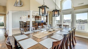 A spacious dining area with a long table, wooden chairs, and hanging lanterns. - Windjammer | 160 ft from the beach | Private Pool, Hot Tub (Virginia Beach)