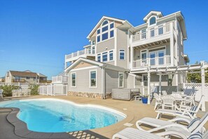 A two-story house with a swimming pool, outdoor furniture, and a stone wall. - Windjammer | 160 ft from the beach | Private Pool, Hot Tub (Virginia Beach)
