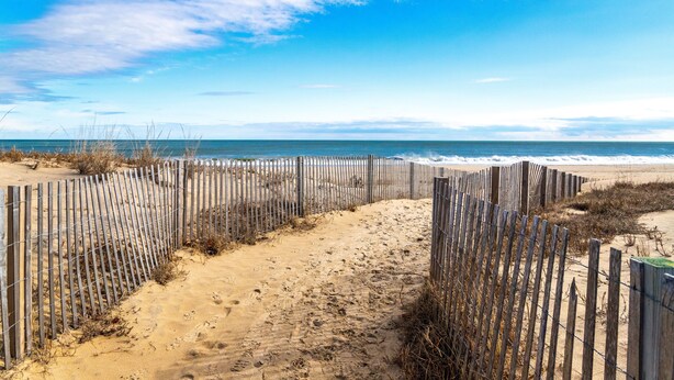 A sandy beach with a wooden fence and a clear blue sky. -  90 Steps to the beach and an ocean view condo in OCMD (Ocean City)