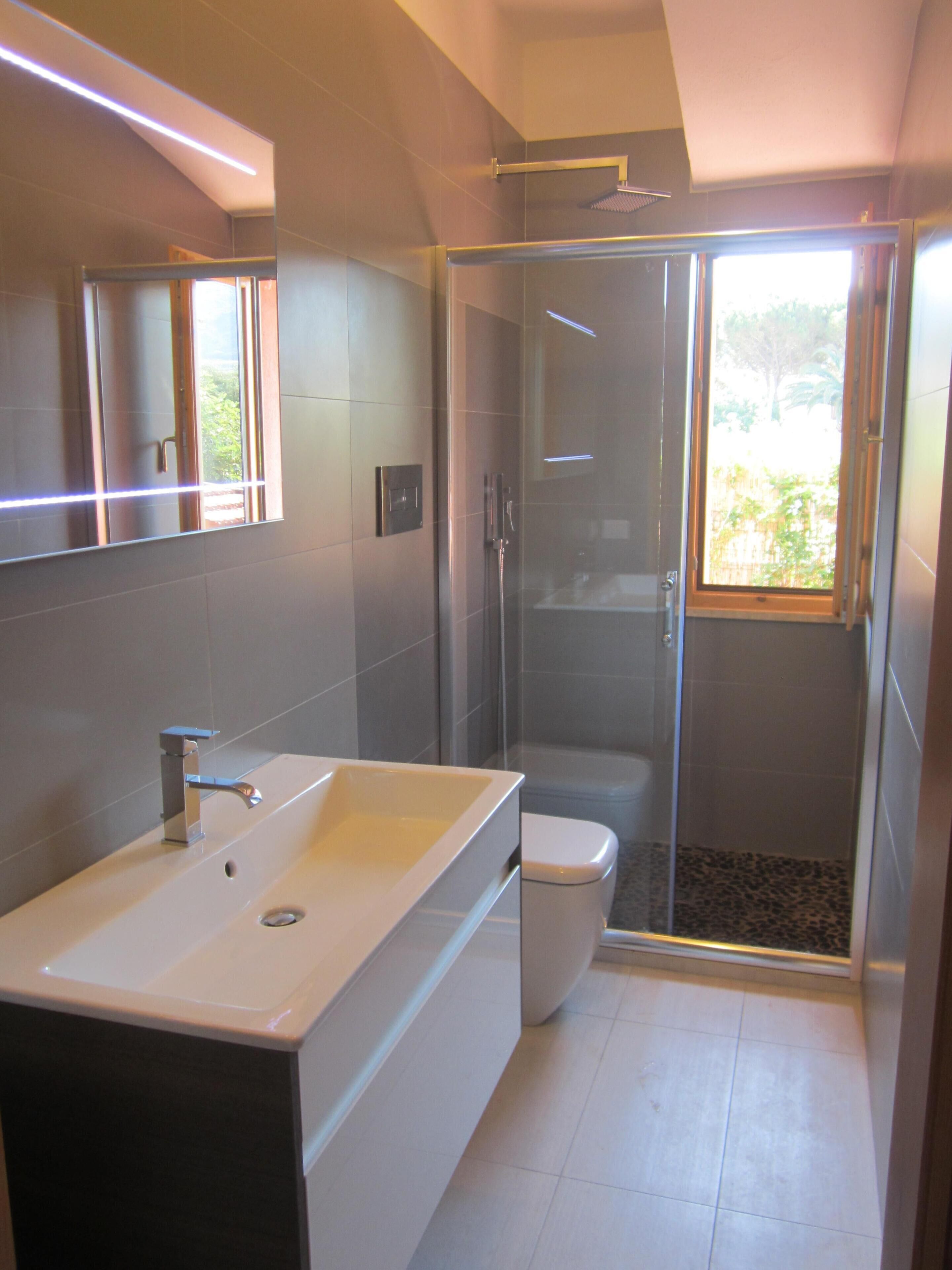 Une salle de bain moderne dotée d’un grand lavabo, de toilettes et d’une douche à parois de verre.