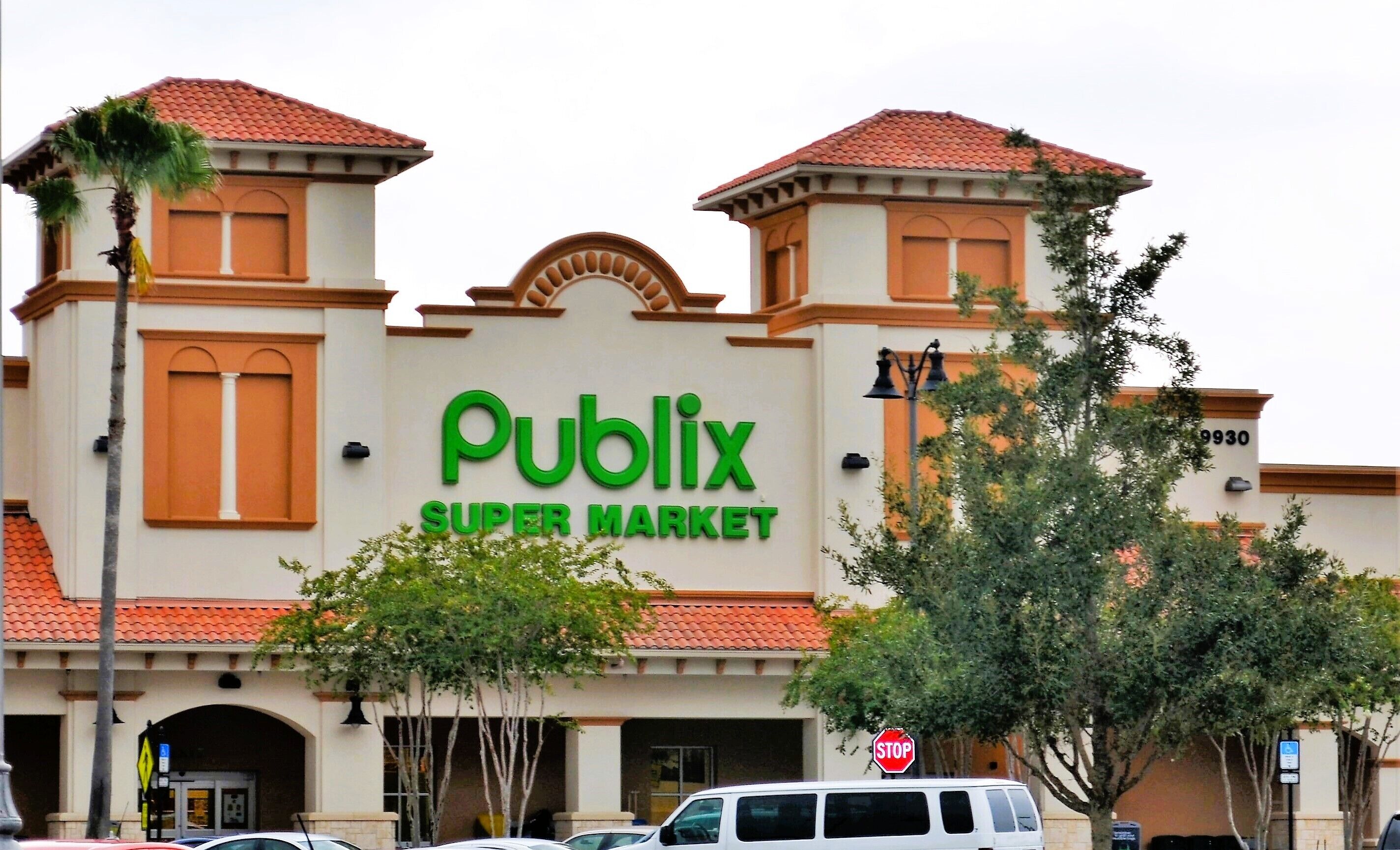 Un supermarché Publix au style architectural traditionnel, caractérisé par un toit recouvert de tuiles rouges et des fenêtres en arc de cercle.