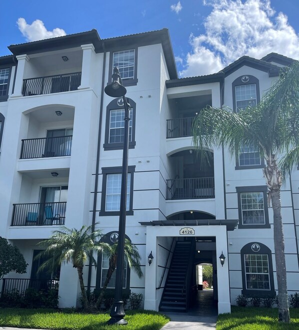 A multi-story building with balconies, a staircase leading to the entrance, and a sign with the number 4126. - Perfect for Families Looking to Spend Quality Time Together Near the Theme Parks (Orlando)