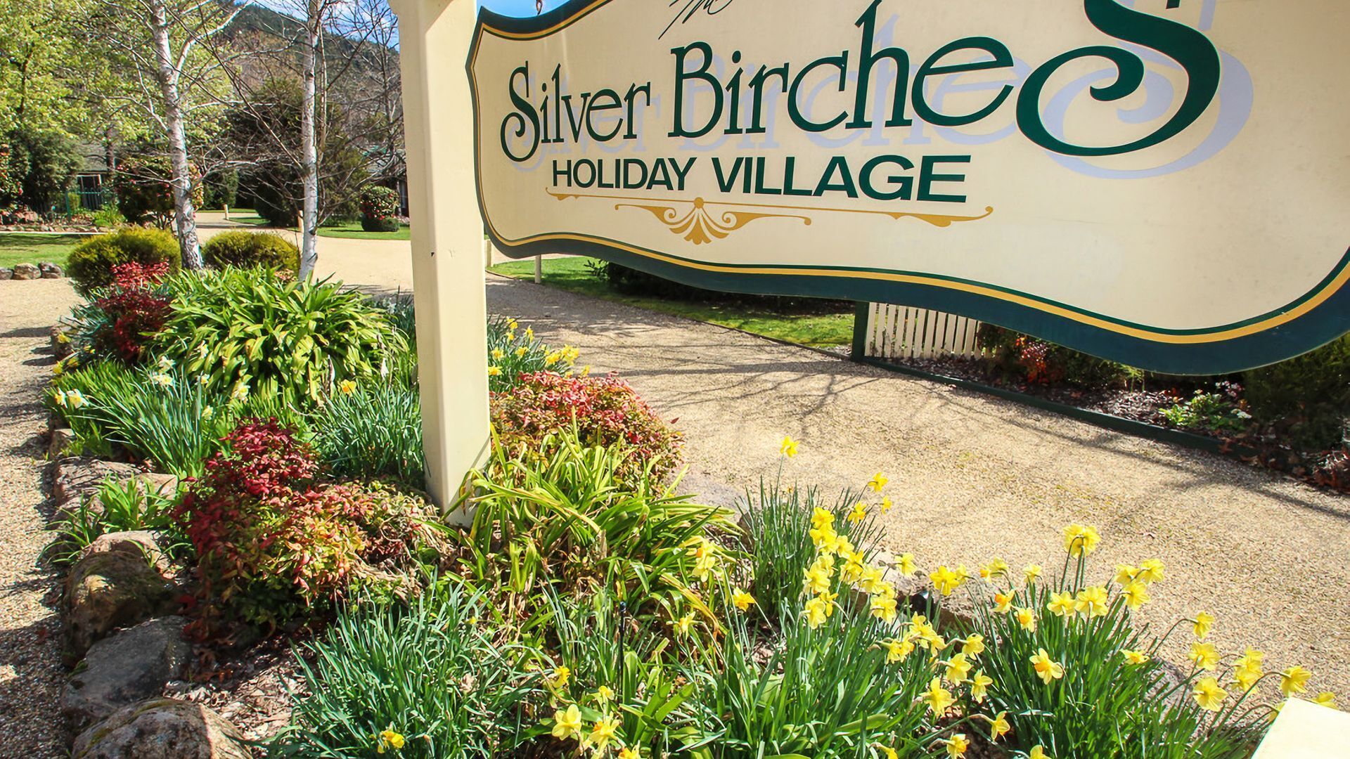 A sign for Silver Birch Holiday Village with a landscaped entrance featuring various plants and flowers.