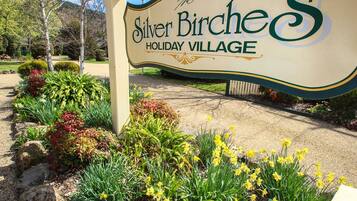 A sign for Silver Birch Holiday Village with a landscaped entrance featuring various plants and flowers.