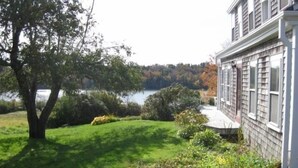 A house with a view of a lake and a well-maintained lawn. - Charming Antique Cape, Water View, Historic Castine, Penobscot Bay. (Castine)