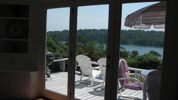 A room with a sliding glass door leading to an outdoor deck with chairs and a grill. - Charming Antique Cape, Water View, Historic Castine, Penobscot Bay. (Castine)