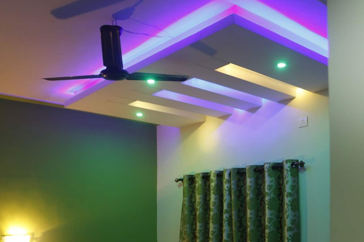 A bedroom with a bed, a ceiling fan, and a wall-mounted light fixture.