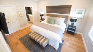 A bedroom with a large bed, bedside tables, a bench, and a door.