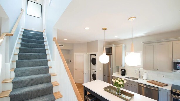 A modern kitchen with stainless steel appliances, a central island, and pendant lighting.