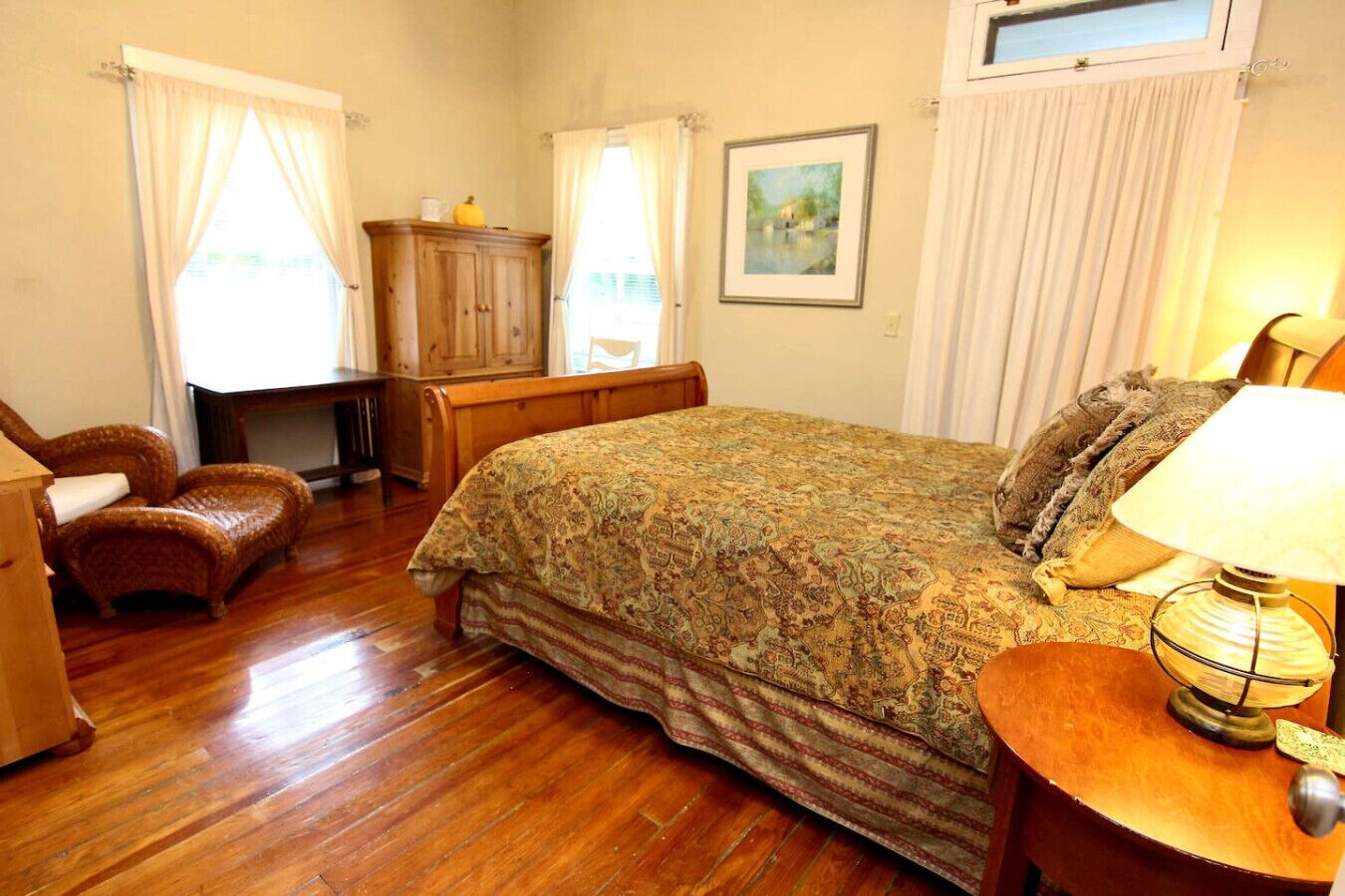 Une chambre à coucher avec un lit en bois, une chaise, un bureau et une lampe.