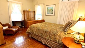 Un dormitorio con una cama de madera, una silla, un escritorio y una lámpara.