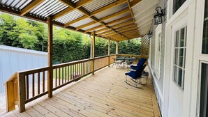 Una terraza de madera con barandilla, una mesa y dos sillas.