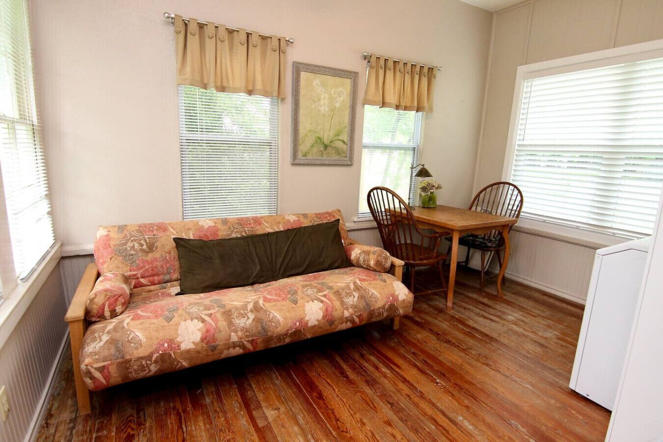 Una habitación acogedora con un sofá floral, una mesa de comedor de madera y dos sillas.