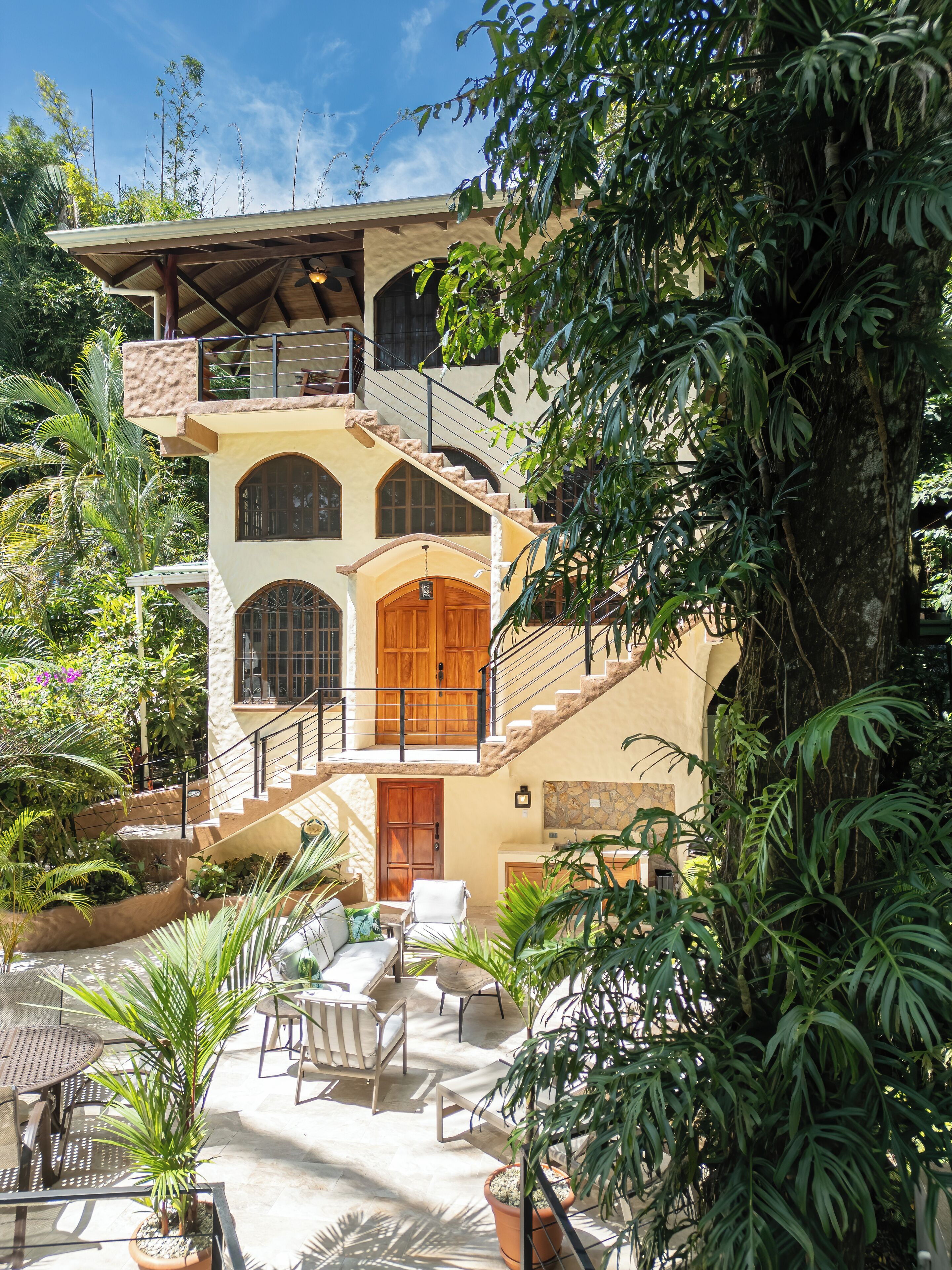 A multi-story building with a balcony, a staircase, and a patio area with outdoor furniture.