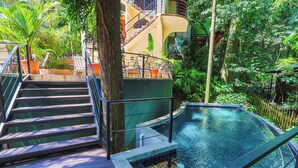 Ein Poolbereich mit Holzterrasse, Treppe und Blick auf üppiges Grün.